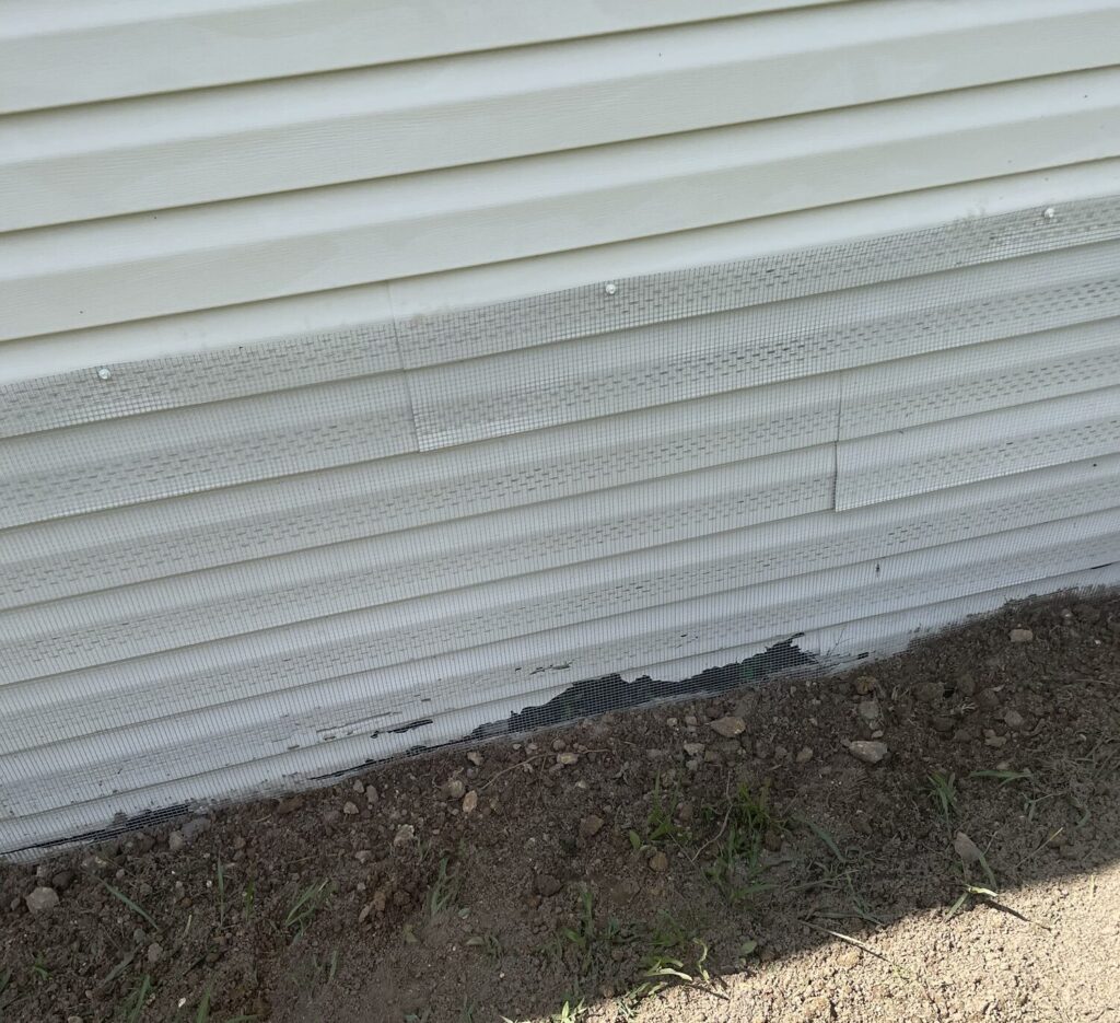 Hudson mobile home protected with hardware cloth barrier tap‑conned into concrete to prevent rodent and wildlife entry beneath structure.