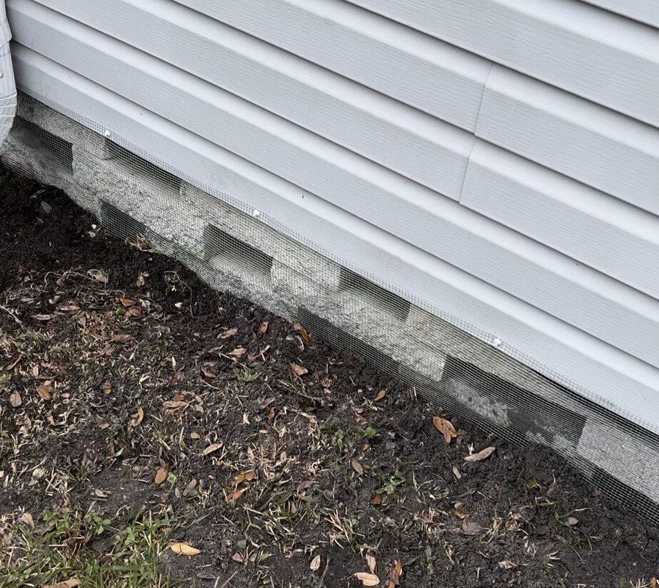Heritage Pines mobile home with hardware cloth barrier (buried or concrete‑mounted), sealed soffits and vents, and optional internal mesh wrap behind skirting.