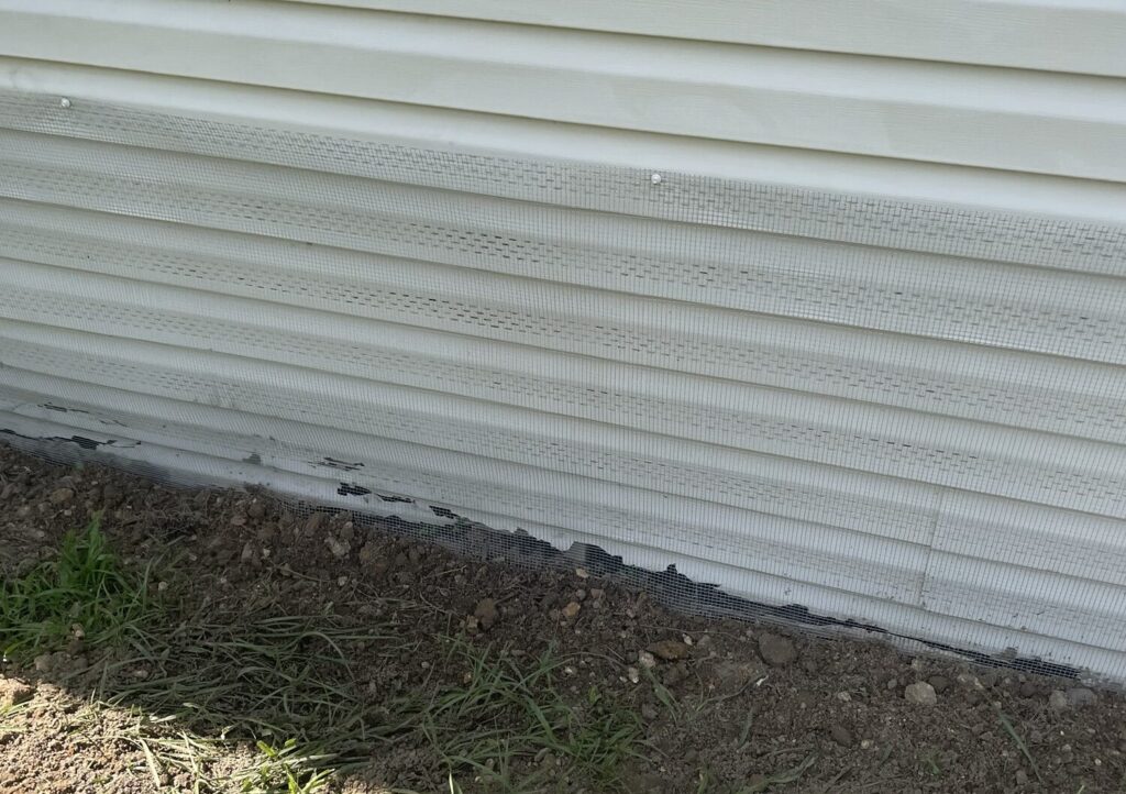 River Ridge mobile home showing hardware cloth barrier (buried or concrete-mounted), soffit and attic vents sealed, with optional interior wrap behind skirting.